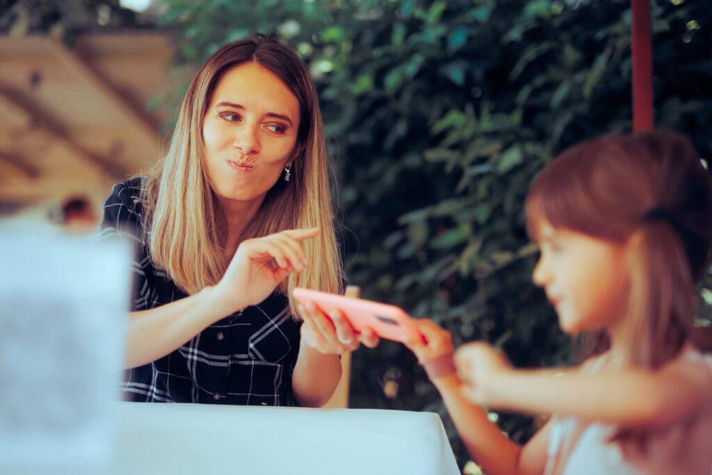 Genitore che da lo smartphone alla figlia